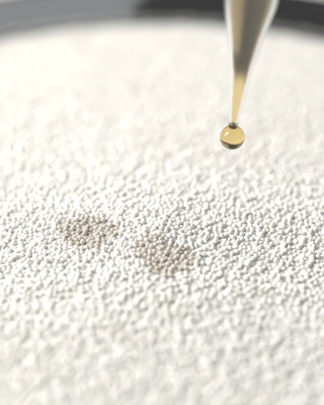 Drops of oil falling from a glass dropper onto white candle pearls